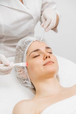 Kozmetik uzmanı modern bir güzellik kliniğinde gelişmiş cilt bakımı tekniklerini vurgulayan bir yüz kremi uyguluyor. Reklamınızda birinci sınıf spa tedavilerini sergilemek için ideal..     