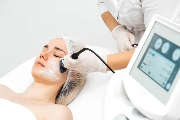 Kozmetik uzmanı modern bir klinikteki genç bir kadına radyasyon kaldırma uyguluyor. Bu gelişmiş işlem cilt bakımını sıkılaştırır ve gençleştirmeyi teşvik eder. Güzellik tedavileri için ideal..