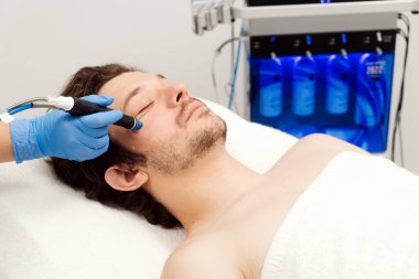 Adam güzellik kliniğinde yüz bakımı görüyor. Bu gelişmiş prosedür cildinizi gençleştirir ve canlandırır. Reklamlarınızda kaliteli cilt bakımı için idealdir..