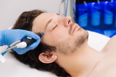 Adam güzellik kliniğinde yüz bakımı görüyor. Bu gelişmiş prosedür cildinizi gençleştirir ve canlandırır. Reklamlarınızda kaliteli cilt bakımı için idealdir..