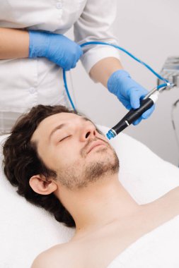 Adam güzellik kliniğinde yüz bakımı görüyor. Bu gelişmiş prosedür cildinizi gençleştirir ve canlandırır. Reklamlarınızda kaliteli cilt bakımı için idealdir..