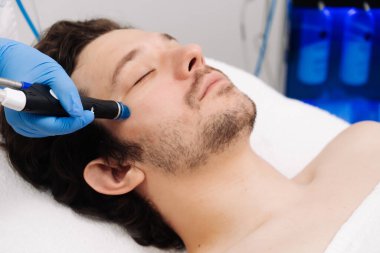 Adam güzellik kliniğinde yüz bakımı görüyor. Bu gelişmiş prosedür cildinizi gençleştirir ve canlandırır. Reklamlarınızda kaliteli cilt bakımı için idealdir..