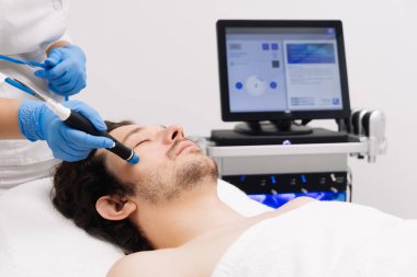 Adam güzellik kliniğinde yüz bakımı görüyor. Bu gelişmiş prosedür cildinizi gençleştirir ve canlandırır. Reklamlarınızda kaliteli cilt bakımı için idealdir..