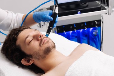 Adam güzellik kliniğinde yüz bakımı görüyor. Bu gelişmiş prosedür cildinizi gençleştirir ve canlandırır. Reklamlarınızda kaliteli cilt bakımı için idealdir..