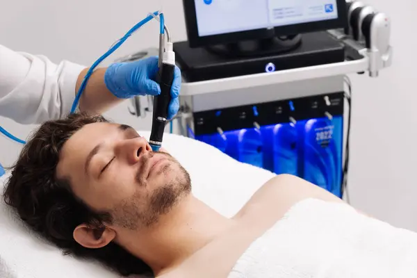 Adam güzellik kliniğinde yüz bakımı görüyor. Bu gelişmiş prosedür cildinizi gençleştirir ve canlandırır. Reklamlarınızda kaliteli cilt bakımı için idealdir..