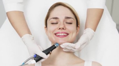 Modern klinikte genç bir kadına hidrojen soyarak tedavi uygulayan profesyonel bir kozmetik uzmanı. Derin cilt temizleme ve gençleştirme üzerine odaklanıyor. Gelişmiş cilt bakımı teknikleri için mükemmel..