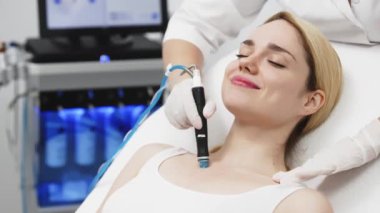 Modern klinikte genç bir kadına hidrojen soyarak tedavi uygulayan profesyonel bir kozmetik uzmanı. Derin cilt temizleme ve gençleştirme üzerine odaklanıyor. Gelişmiş cilt bakımı teknikleri için mükemmel..