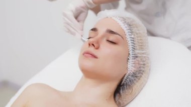 Kozmetik uzmanı modern bir güzellik kliniğinde gelişmiş cilt bakımı tekniklerini vurgulayan bir yüz kremi uyguluyor. Reklamınızda birinci sınıf spa tedavilerini sergilemek için ideal..     