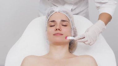 Kozmetik uzmanı modern bir güzellik kliniğinde gelişmiş cilt bakımı tekniklerini vurgulayan bir yüz kremi uyguluyor. Reklamınızda birinci sınıf spa tedavilerini sergilemek için ideal..     