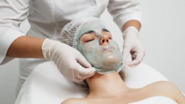 Kozmetik uzmanı modern bir kuaförde genç bir kadına aljinat maske takıyor.. 