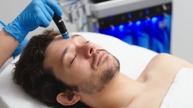 Adam güzellik kliniğinde yüz bakımı görüyor. Bu gelişmiş prosedür cildinizi gençleştirir ve canlandırır. Reklamlarınızda kaliteli cilt bakımı için idealdir..