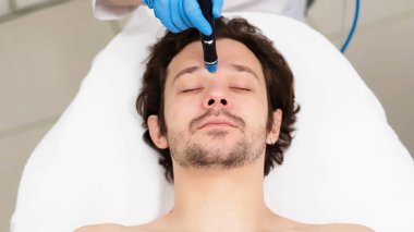 Man undergoes a hydrofacial treatment at a beauty clinic. This advanced procedure rejuvenates and revitalizes the skin, ideal for showcasing premium skincare services in your advertising. clipart