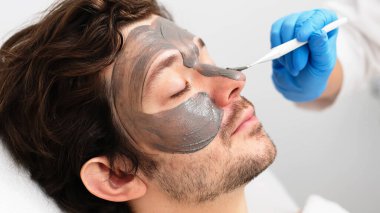 Yakışıklı bir adam güzellik uzmanından gençleştirici bir maske alır. Reklamınızda cilt gerdirme ve gelişmiş cilt bakımı. Profesyonel yüz bakımı için mükemmel..