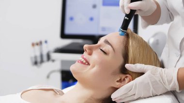 Modern klinikte genç bir kadına hidrojen soyarak tedavi uygulayan profesyonel bir kozmetik uzmanı. Derin cilt temizleme ve gençleştirme üzerine odaklanıyor. Gelişmiş cilt bakımı teknikleri için mükemmel..