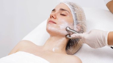 Kozmetik uzmanı yüz gençleştirme ve sıkma için RF kaldırma ameliyatı yapıyor. Bu müdahale etmeyen prosedür cildinizi sertleştirir ve pürüzsüzleştirir. Güzellik rutininizi geliştirir..