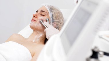 Kozmetik uzmanı yüz gençleştirme ve sıkma için RF kaldırma ameliyatı yapıyor. Bu müdahale etmeyen prosedür cildinizi sertleştirir ve pürüzsüzleştirir. Güzellik rutininizi geliştirir..