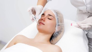 Kozmetik uzmanı modern bir güzellik kliniğinde gelişmiş cilt bakımı tekniklerini vurgulayan bir yüz kremi uyguluyor. Reklamınızda birinci sınıf spa tedavilerini sergilemek için ideal..     