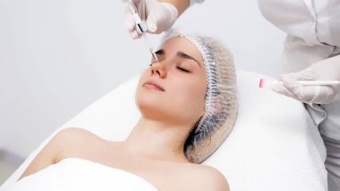 Kozmetik uzmanı modern bir güzellik kliniğinde gelişmiş cilt bakımı tekniklerini vurgulayan bir yüz kremi uyguluyor. Reklamınızda birinci sınıf spa tedavilerini sergilemek için ideal..     