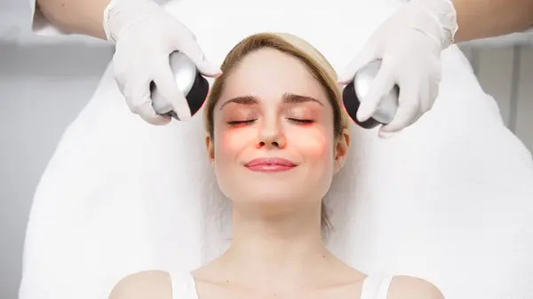 stock image Cosmetologist performs LED light therapy for facial rejuvenation. This non-invasive treatment improves skin elasticity, reduces aging signs, and enhances overall skin radiance.