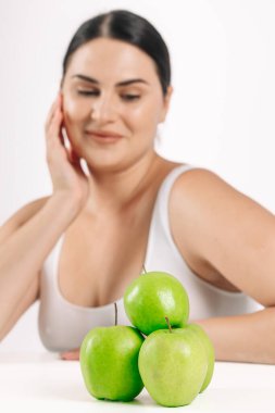 Stüdyoda yeşil elmalarla poz veren genç ve güzel bir kız sağlıklı beslenme ve diyet konsepti.