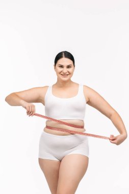 Beyaz arka planda mezurası olan kilolu bir kadın.