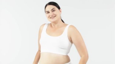 Stüdyoda açık gri arka planda poz veren güzel, gülümseyen kıvrımlı kadın. güzellik, sağlık, vücut bakımı, kozmetoloji, cilt bakımı kavramı