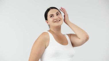 Stüdyoda açık gri arka planda poz veren güzel, gülümseyen kıvrımlı kadın. güzellik, sağlık, vücut bakımı, kozmetoloji, cilt bakımı kavramı