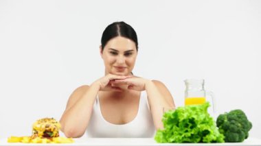 young female model choosing between burger and healthy food, diet concept