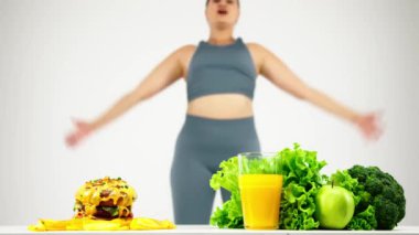 Hamburger sağlıklı gıdaya karşı, diyet konsepti, bulanık arka planda egzersiz yapan genç, kıvrımlı kadın.