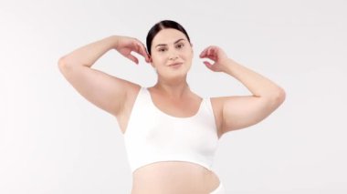 Stüdyoda açık gri arka planda poz veren güzel, gülümseyen kıvrımlı kadın. güzellik, sağlık, vücut bakımı, kozmetoloji, cilt bakımı kavramı