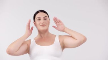 Stüdyoda açık gri arka planda poz veren güzel, gülümseyen kıvrımlı kadın. güzellik, sağlık, vücut bakımı, kozmetoloji, cilt bakımı kavramı