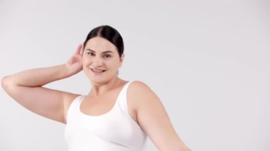 Stüdyoda açık gri arka planda poz veren güzel, gülümseyen kıvrımlı kadın. güzellik, sağlık, vücut bakımı, kozmetoloji, cilt bakımı kavramı