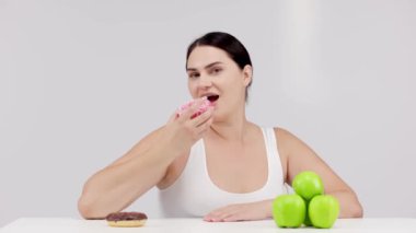 Çörek ve yeşil elma arasında seçim yapan genç bir kadın, diyet kavramı.