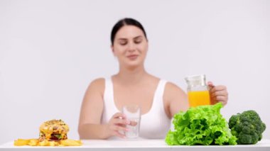 Hamburger ve sağlıklı yiyecek arasında seçim yapan genç bir kadın model.