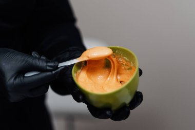 Bir kozmetikçinin aljinat yüz maskesi hazırladığı yakın plan. Bu kaliteli tedavi cilt hidrasyonu ve gençleşmesi için mükemmel bir örnek.