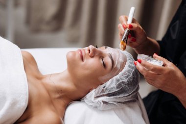 Gencecik, rahat bir kadının dış görünüş portresi cilt geliştirme prosedürü üzerine. Nemlendirici için özel maske ve krem kavramı. Kişisel bakım spa konsepti. Kozmetik bilimi reklamı, temizlik