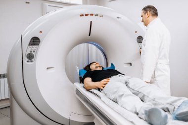 İşlem hazırlıkları sırasında bilgisayarlı tomografi tarayıcısında gözden kaçan erkek doktor.      