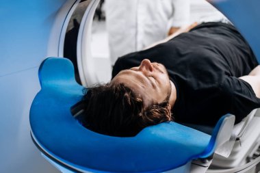 Modern hastanedeki MR makinesindeki genç adam.               