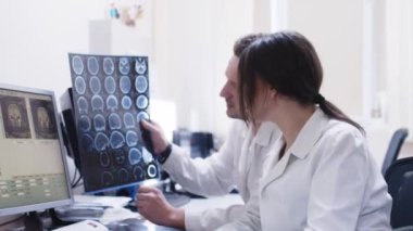 Genç adam ve kadın doktorlar klinikteki röntgen görüntülerine bakıyorlar.