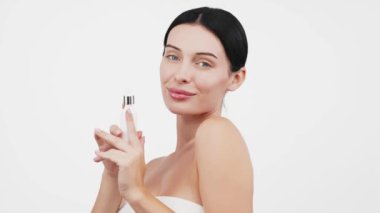 Güzel esmer kadının portresi beyaz arka planda serum uyguluyor.           