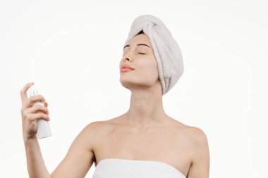 Kozmetik ürünlerle uğraşan genç bir kadının portresi. Vücudunda ve saç bakımında hidratasyon ve parlaklığın önemini vurgulayarak özgüven yayıyor..