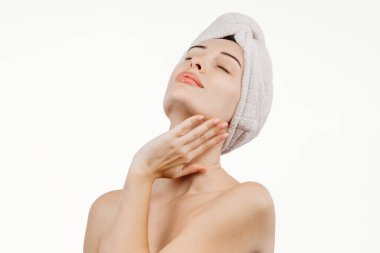 Kafasında havluyla tenine dokunan güzel genç bir kadın beyaz arka planda izole edilmiş.    