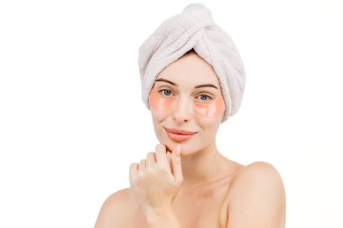 Kafasında havluyla ve gözlerinin altında beyaz arka planda izole edilmiş yamalar olan güzel genç bir kadın.                     