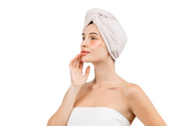 Kafasında havluyla ve gözlerinin altında beyaz arka planda izole edilmiş yamalar olan güzel genç bir kadın.                     