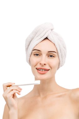 Güzellik ve kişisel hijyen kavramı. Banyo havlusu içinde çekici, mutlu bir genç kadın elinde bir diş fırçası tutuyor..  