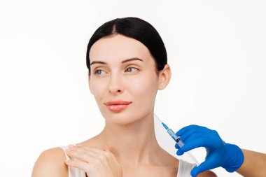 Genç ve güzel bir kadın beyaz bir stüdyo geçmişine karşı botoks yaptırıyor..