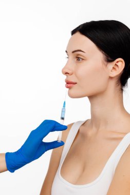 Genç ve güzel bir kadın beyaz bir stüdyo geçmişine karşı botoks yaptırıyor..
