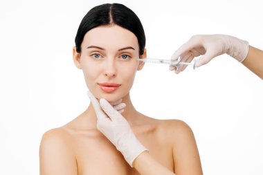 Genç ve güzel bir kadın beyaz bir stüdyo geçmişine karşı botoks yaptırıyor..