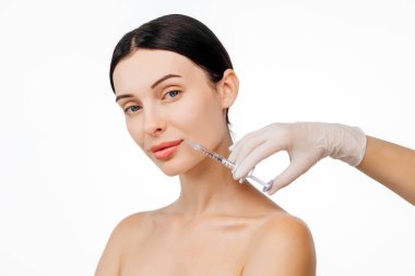 Doktor eli, kadın yüzüne yakın bir şırınga tutuyor ve cilt kaldırma iğnesi oluyor. Bu anda güzellik ve modern cilt teknikleri ışıltılı bir görünüm için vurgulanıyor..