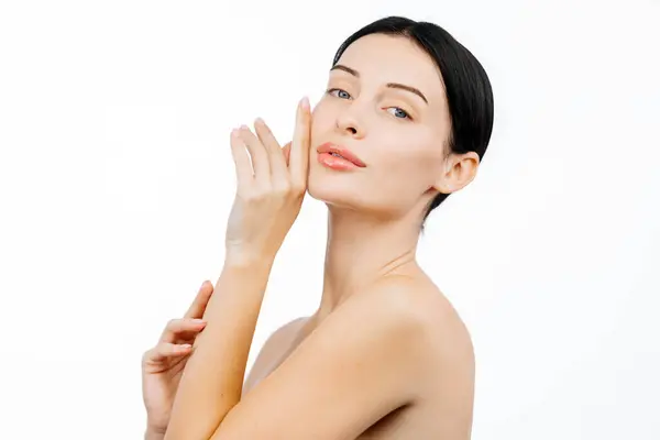 Beyaz arka planda poz veren kusursuz cilde sahip güzel genç bir kadının portresi.           